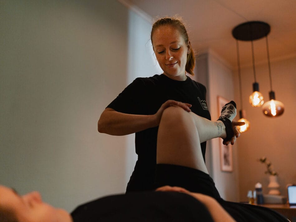 Manueeltherapeut onderzoekt heup bij patient in behandelkamer